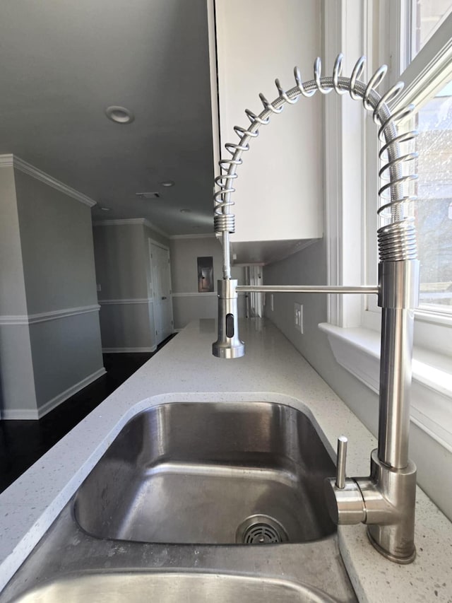 interior details with visible vents, crown molding, and light stone countertops