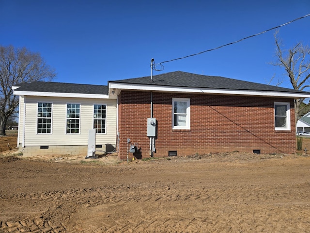 back of house with roof with shingles, brick siding, and crawl space