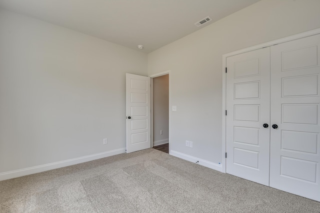 unfurnished bedroom featuring carpet, visible vents, a closet, and baseboards