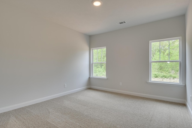 empty room featuring visible vents, light colored carpet, and baseboards