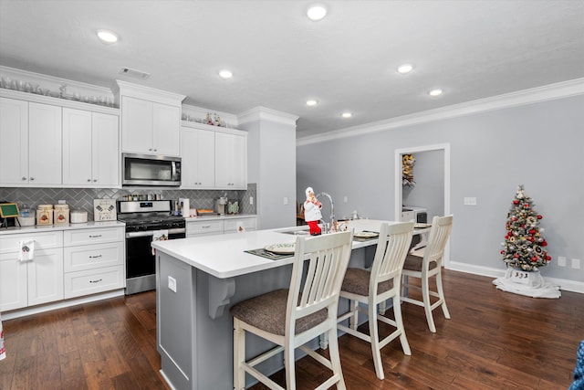 kitchen featuring white cabinets, appliances with stainless steel finishes, a kitchen island with sink, and sink