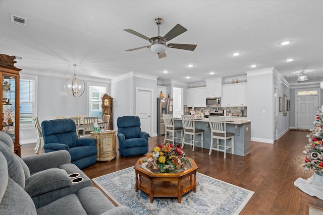 living room featuring ceiling fan with notable chandelier, dark hardwood / wood-style floors, and ornamental molding