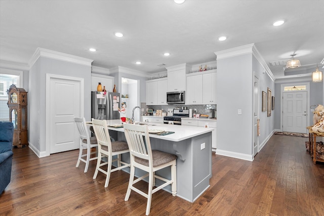 kitchen with a breakfast bar, white cabinets, sink, an island with sink, and appliances with stainless steel finishes