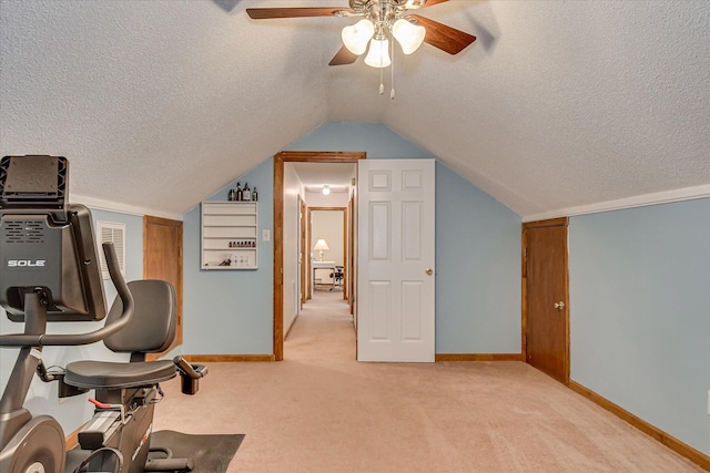 exercise room featuring vaulted ceiling, ceiling fan, light carpet, and baseboards