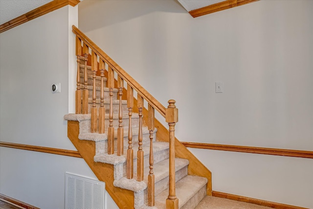 staircase with carpet, visible vents, baseboards, and ornamental molding