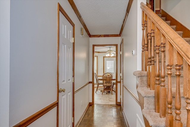 hallway with baseboards, stairway, crown molding, and a textured ceiling