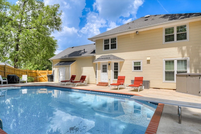 rear view of property featuring fence, a patio, and a fenced in pool