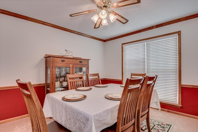 carpeted dining room with baseboards, a ceiling fan, and ornamental molding