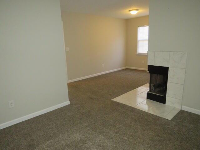 unfurnished living room with a fireplace, carpet flooring, and baseboards