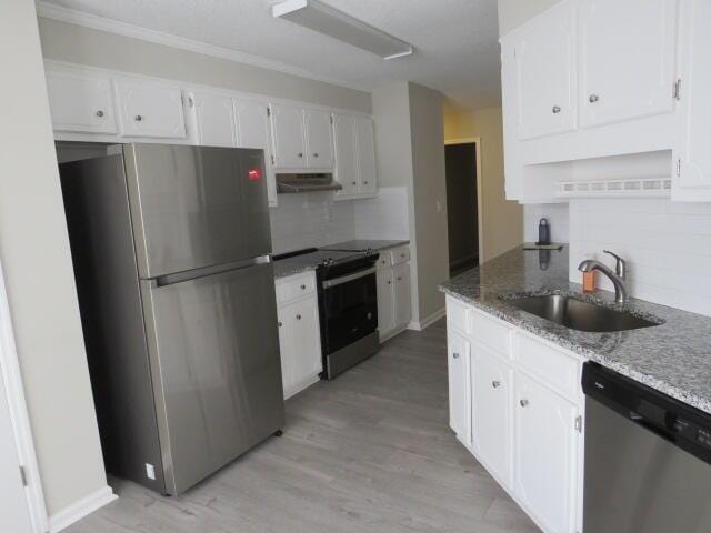 kitchen featuring under cabinet range hood, a sink, white cabinetry, appliances with stainless steel finishes, and light stone countertops