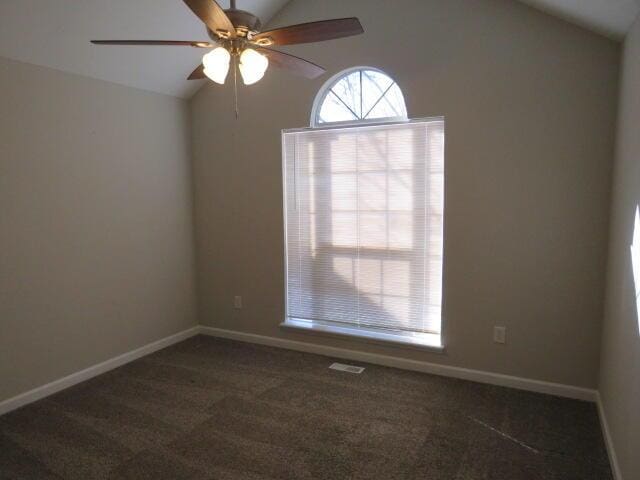 spare room with lofted ceiling, dark carpet, and baseboards