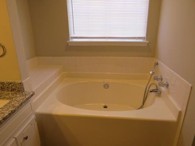 full bath featuring a garden tub and vanity