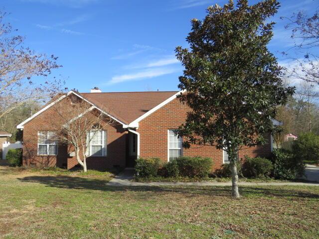 ranch-style house featuring a front lawn, a chimney, and brick siding