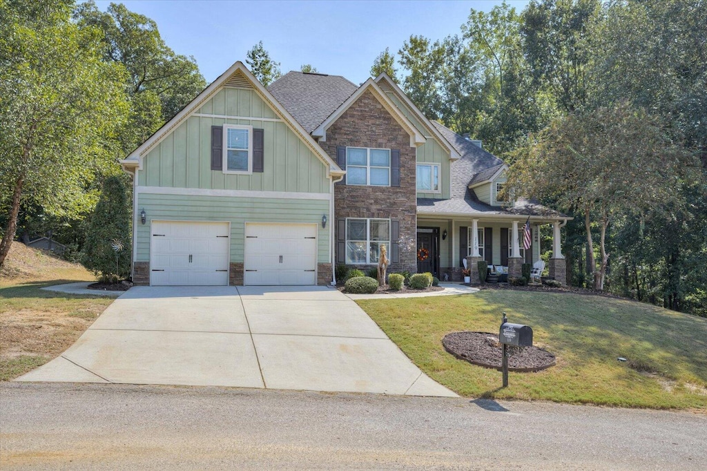 craftsman-style house featuring a porch, a garage, and a front yard