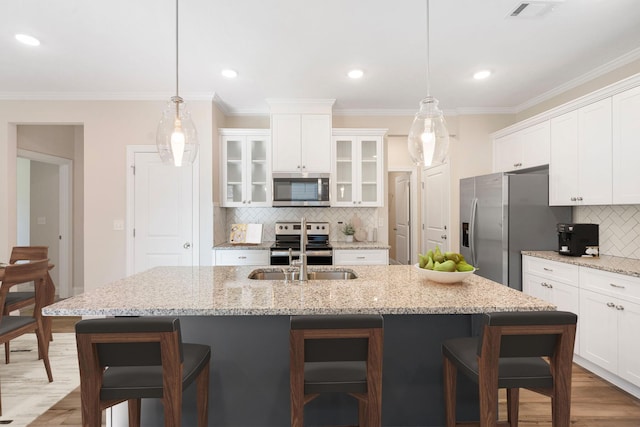 kitchen featuring hanging light fixtures, a kitchen bar, stainless steel appliances, and a center island with sink