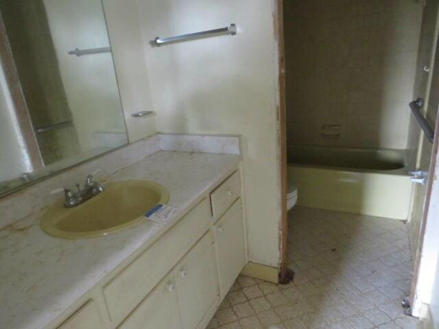 bathroom with toilet, vanity,  shower combination, and tile patterned floors