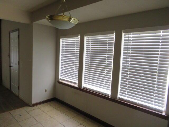 unfurnished dining area featuring light tile patterned floors and baseboards