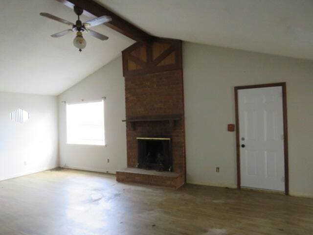 unfurnished living room with vaulted ceiling with beams, a brick fireplace, a ceiling fan, and wood finished floors