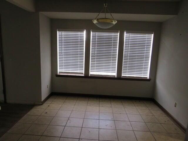 unfurnished room featuring light tile patterned floors and baseboards