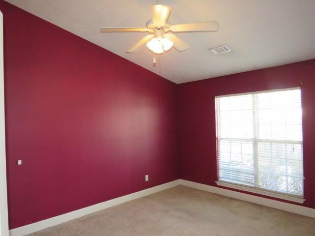 carpeted spare room featuring plenty of natural light and ceiling fan