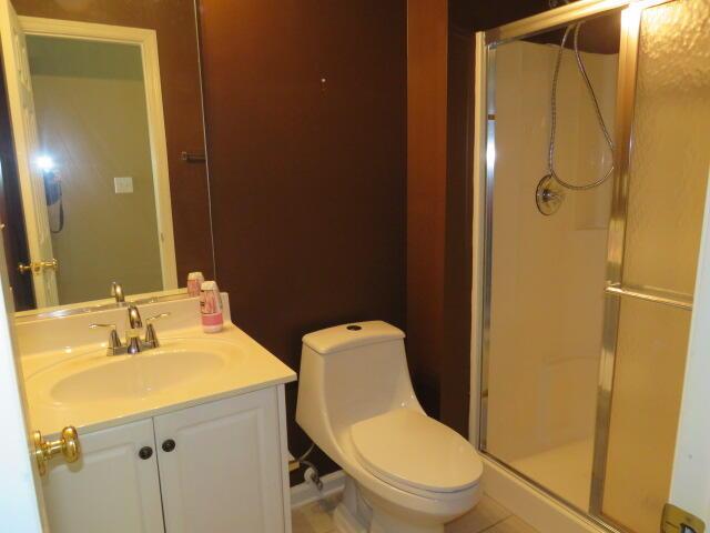 bathroom featuring vanity, a shower with shower door, and toilet