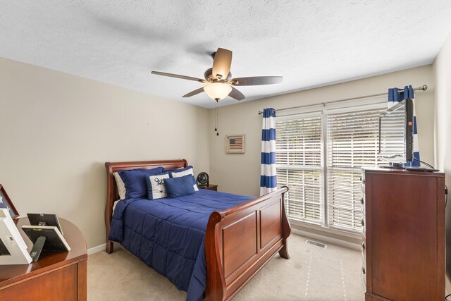 bedroom featuring light colored carpet, a ceiling fan, a textured ceiling, and baseboards