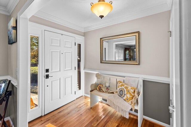 foyer entrance with wood finished floors and crown molding