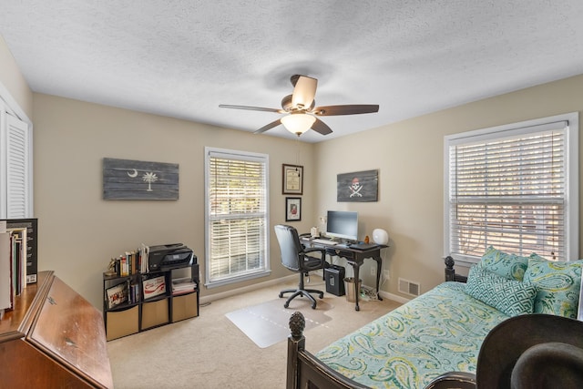 carpeted bedroom featuring an office area, baseboards, a textured ceiling, ceiling fan, and a closet