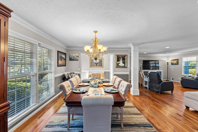 dining space with light wood-style flooring, a textured ceiling, a chandelier, ornamental molding, and recessed lighting