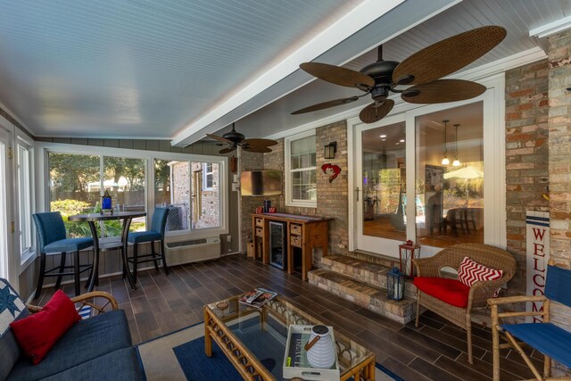 sunroom with a ceiling fan, wood finished floors, beamed ceiling, brick wall, and wine cooler
