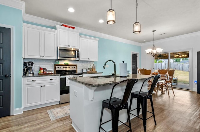 kitchen featuring white cabinets, a center island with sink, an inviting chandelier, and appliances with stainless steel finishes