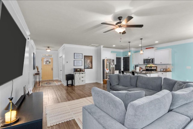 living room featuring ceiling fan, wood-type flooring, and crown molding