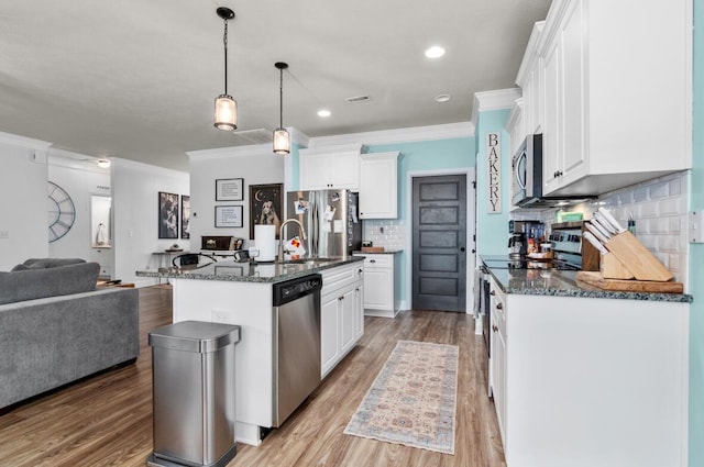 kitchen with pendant lighting, a center island with sink, decorative backsplash, white cabinetry, and stainless steel appliances