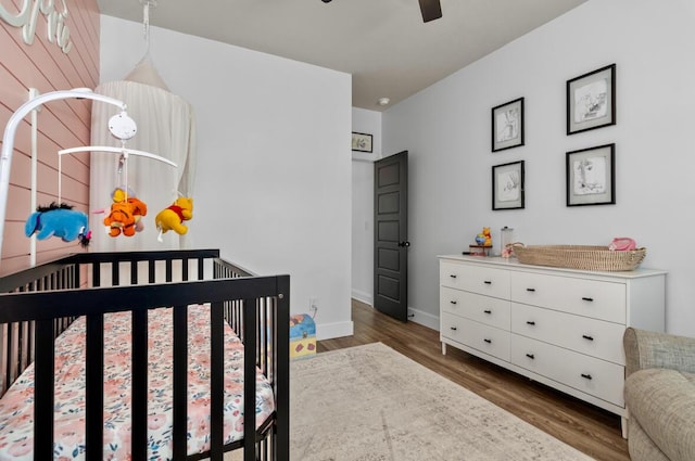 bedroom featuring a crib and dark hardwood / wood-style flooring