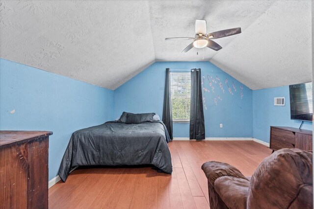 bedroom featuring hardwood / wood-style floors, a textured ceiling, vaulted ceiling, and ceiling fan