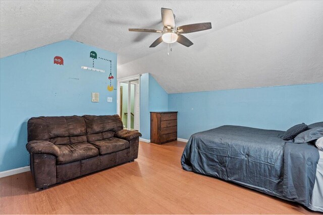 bedroom featuring a textured ceiling, hardwood / wood-style flooring, vaulted ceiling, and ceiling fan