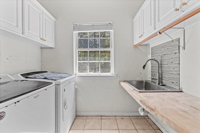 laundry area with light tile patterned flooring, cabinets, separate washer and dryer, and sink