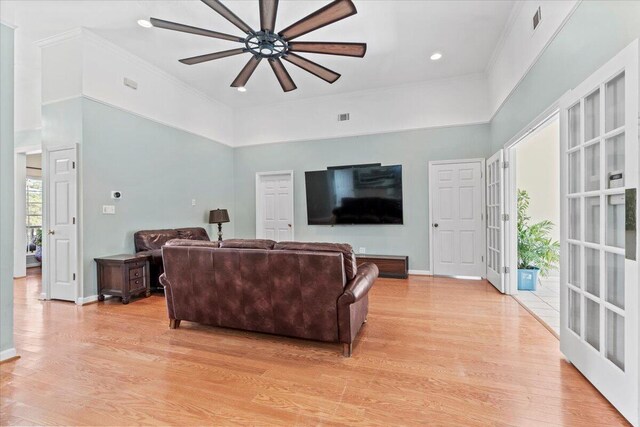 living room featuring ceiling fan, french doors, a high ceiling, and light wood-type flooring