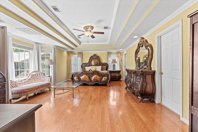 bedroom with a tray ceiling, crown molding, and light hardwood / wood-style floors