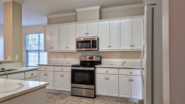 kitchen featuring appliances with stainless steel finishes, white cabinetry, ornamental molding, and a textured ceiling