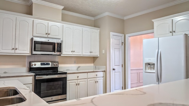 kitchen with appliances with stainless steel finishes, white cabinetry, crown molding, and light stone countertops