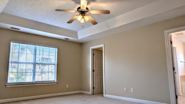 empty room featuring baseboards, a raised ceiling, visible vents, and a ceiling fan