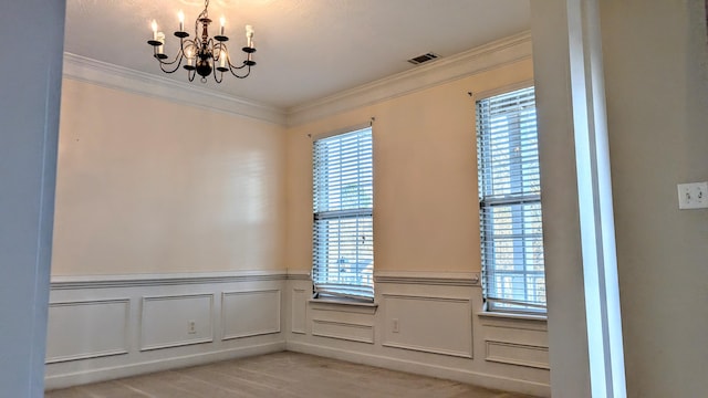 empty room featuring crown molding, visible vents, light wood-style floors, wainscoting, and a chandelier