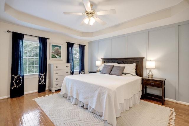 225 Old Mill Rd, Martinez, GA 30907 - bedroom with multiple windows, light wood-style flooring, a raised ceiling, a ceiling fan, and a decorative wall