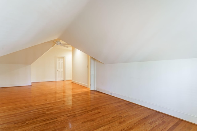 bonus room featuring lofted ceiling, light wood-style floors, and baseboards