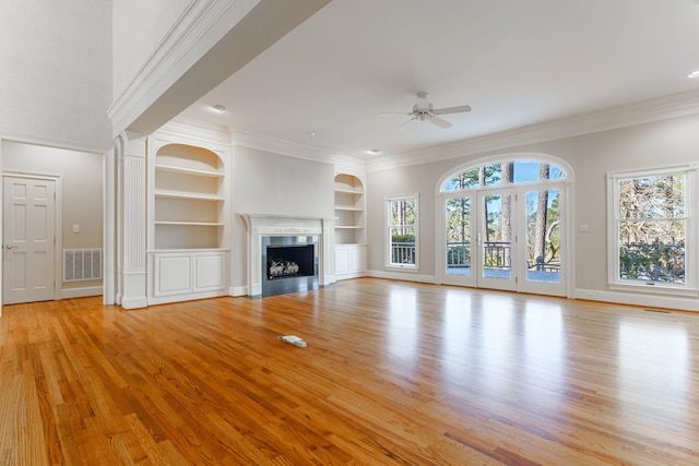 unfurnished living room with visible vents, built in features, a fireplace with flush hearth, ceiling fan, and light wood-type flooring