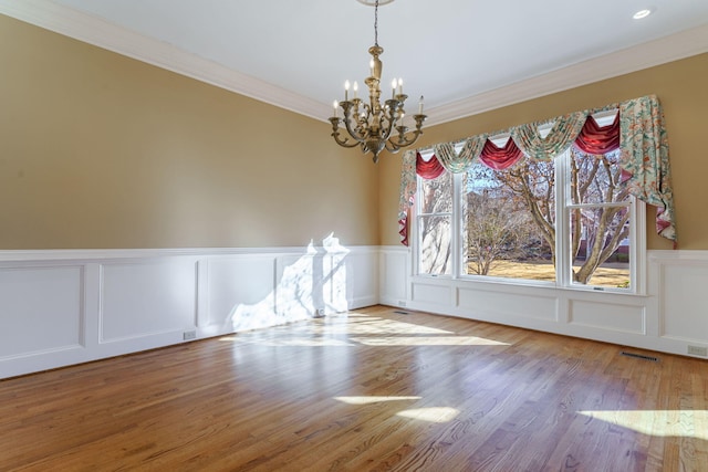 unfurnished dining area with ornamental molding, visible vents, a notable chandelier, and light wood-style flooring