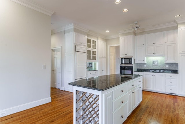 kitchen with light wood finished floors, white cabinets, decorative backsplash, glass insert cabinets, and black appliances