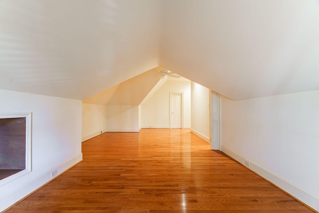 additional living space with light wood-style floors, baseboards, and vaulted ceiling