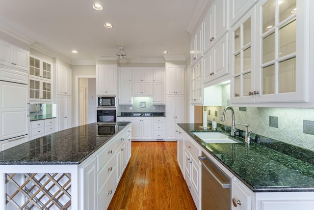 kitchen featuring a kitchen island, a sink, white cabinets, black appliances, and glass insert cabinets